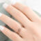  A hand with rose gold diamond-textured stacking rings, against a blurred green velvet backdrop. 
